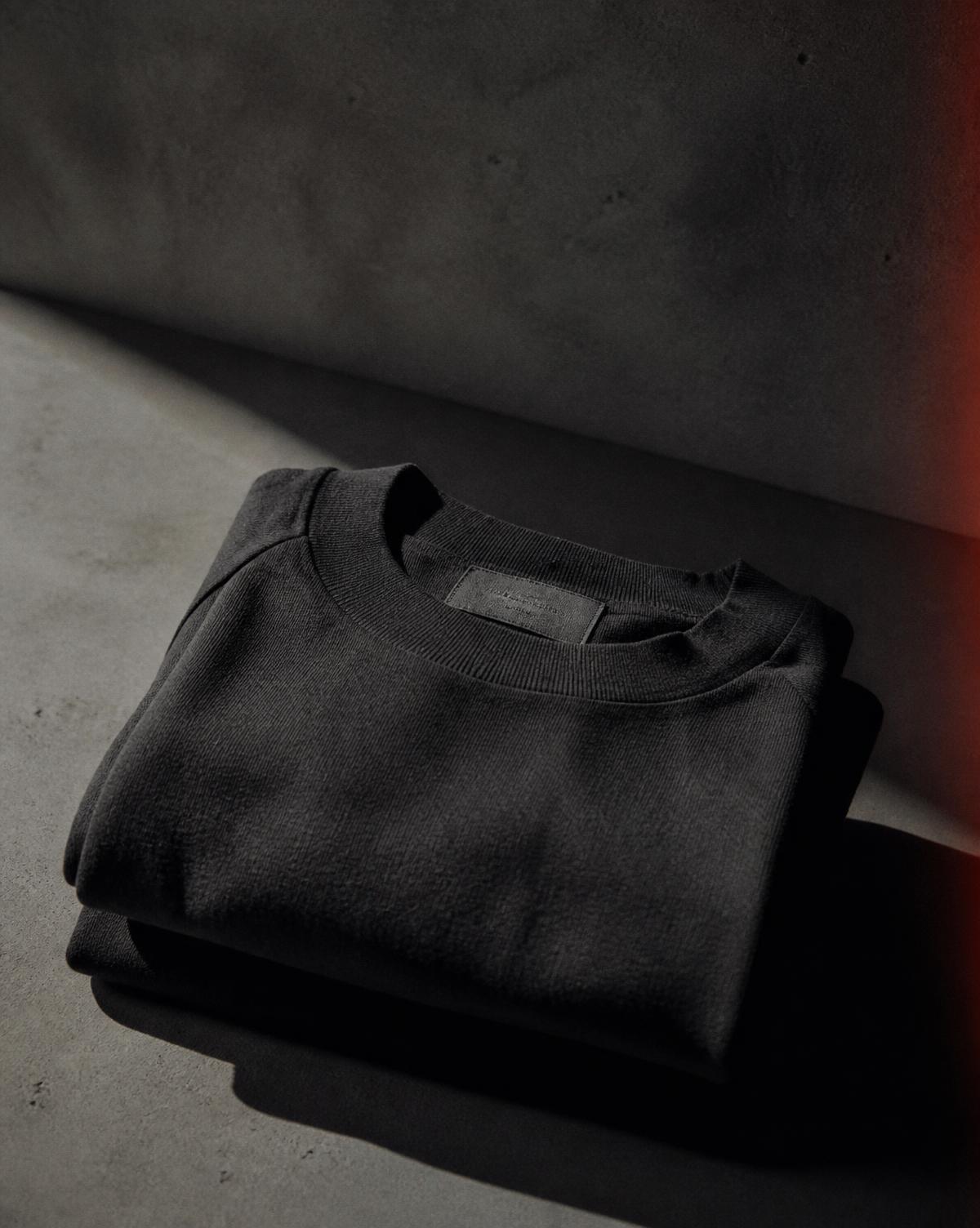 Folded heavyweight charcoal garment on concrete